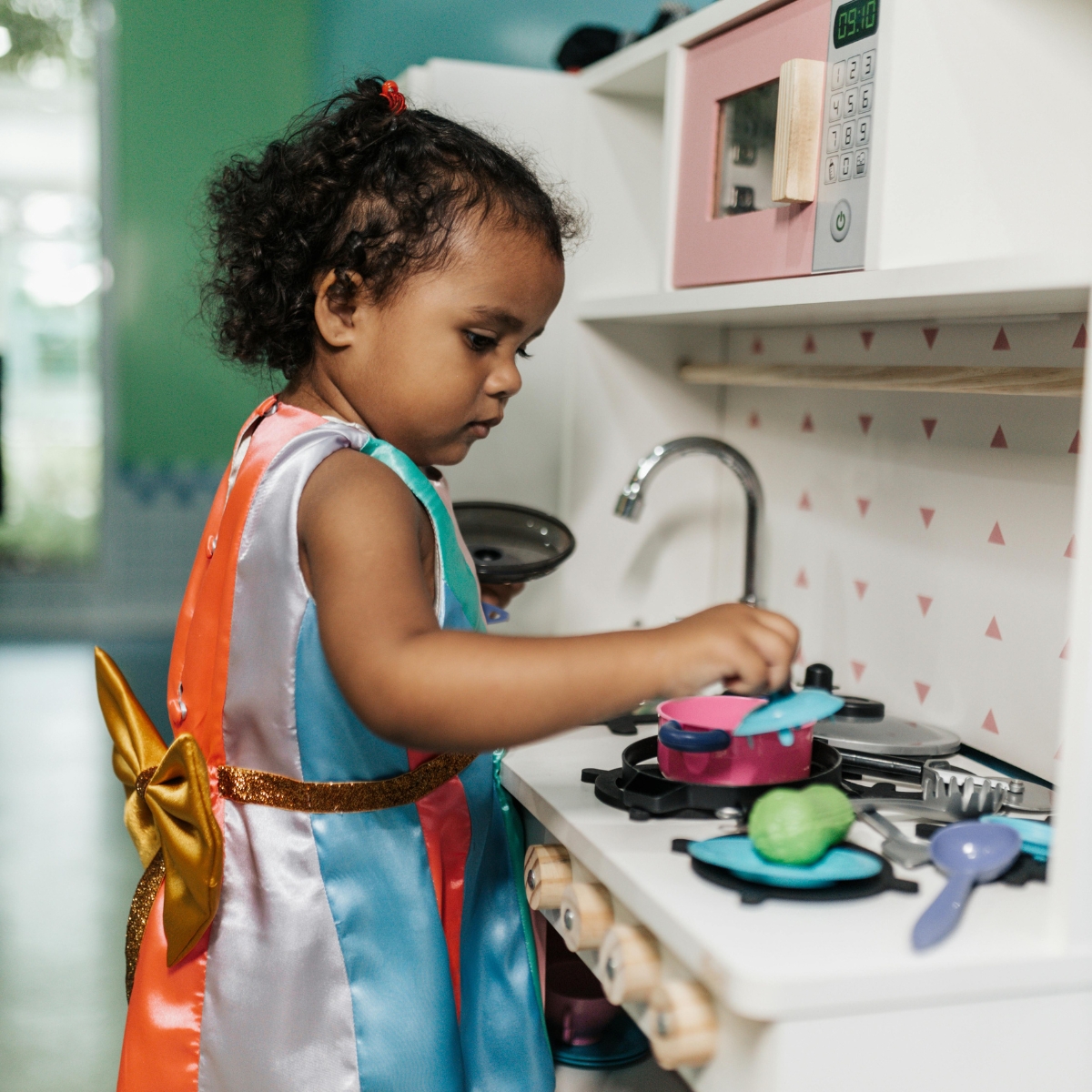 a girl kid playing with kitchen set